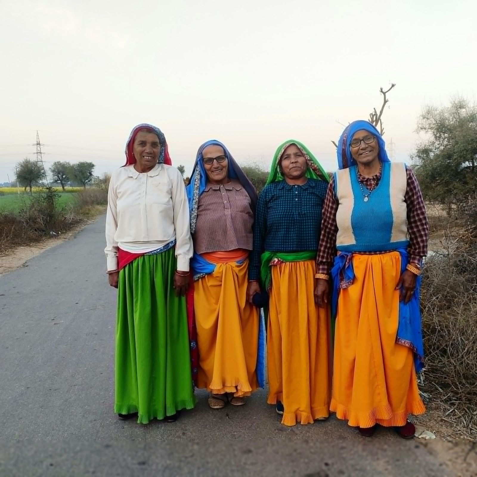 Four village women standing together on a rural road
